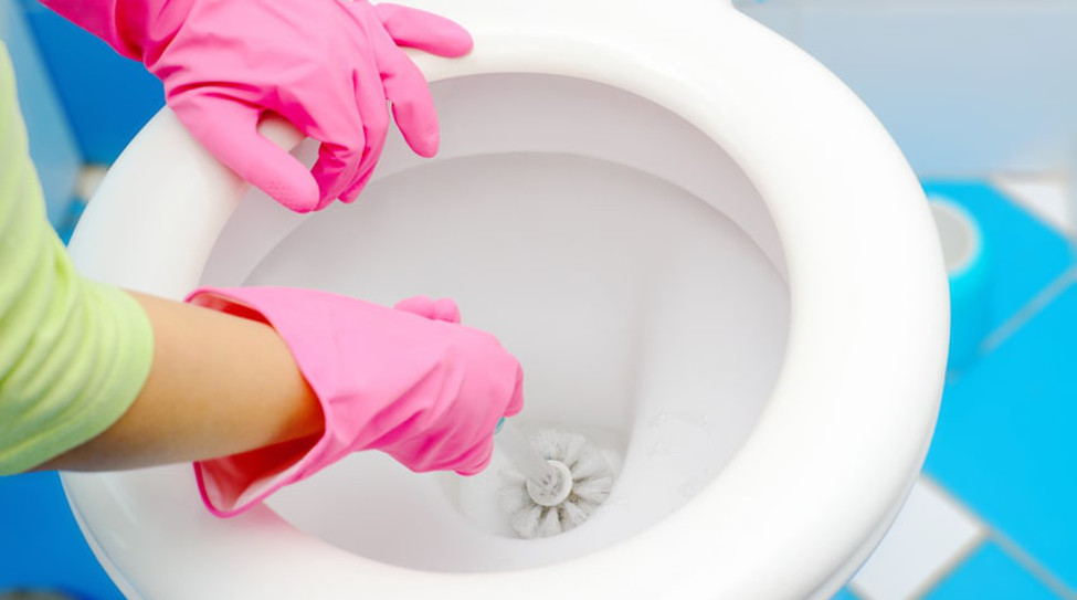 Toilette verstopft: Frau reinigt WC mit Klobürste